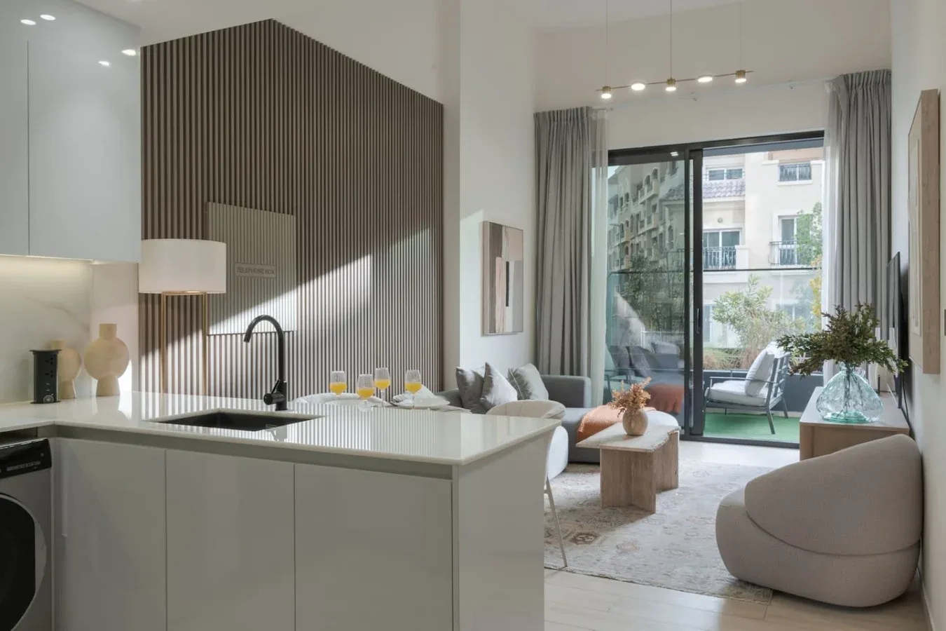 A modern open-plan kitchen and living area opens onto a balcony.