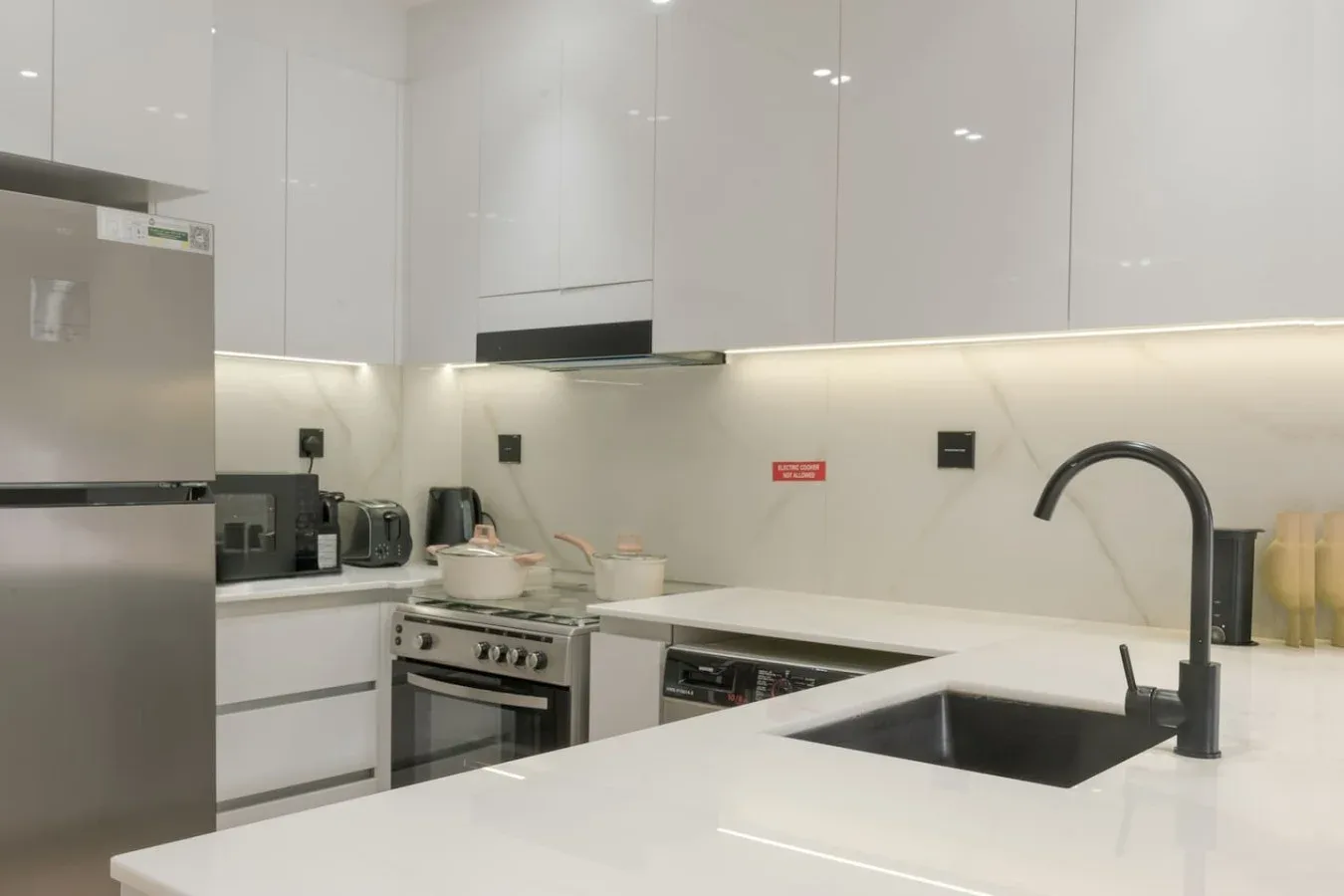 A bright modern kitchen with white cabinets and a dark sink.