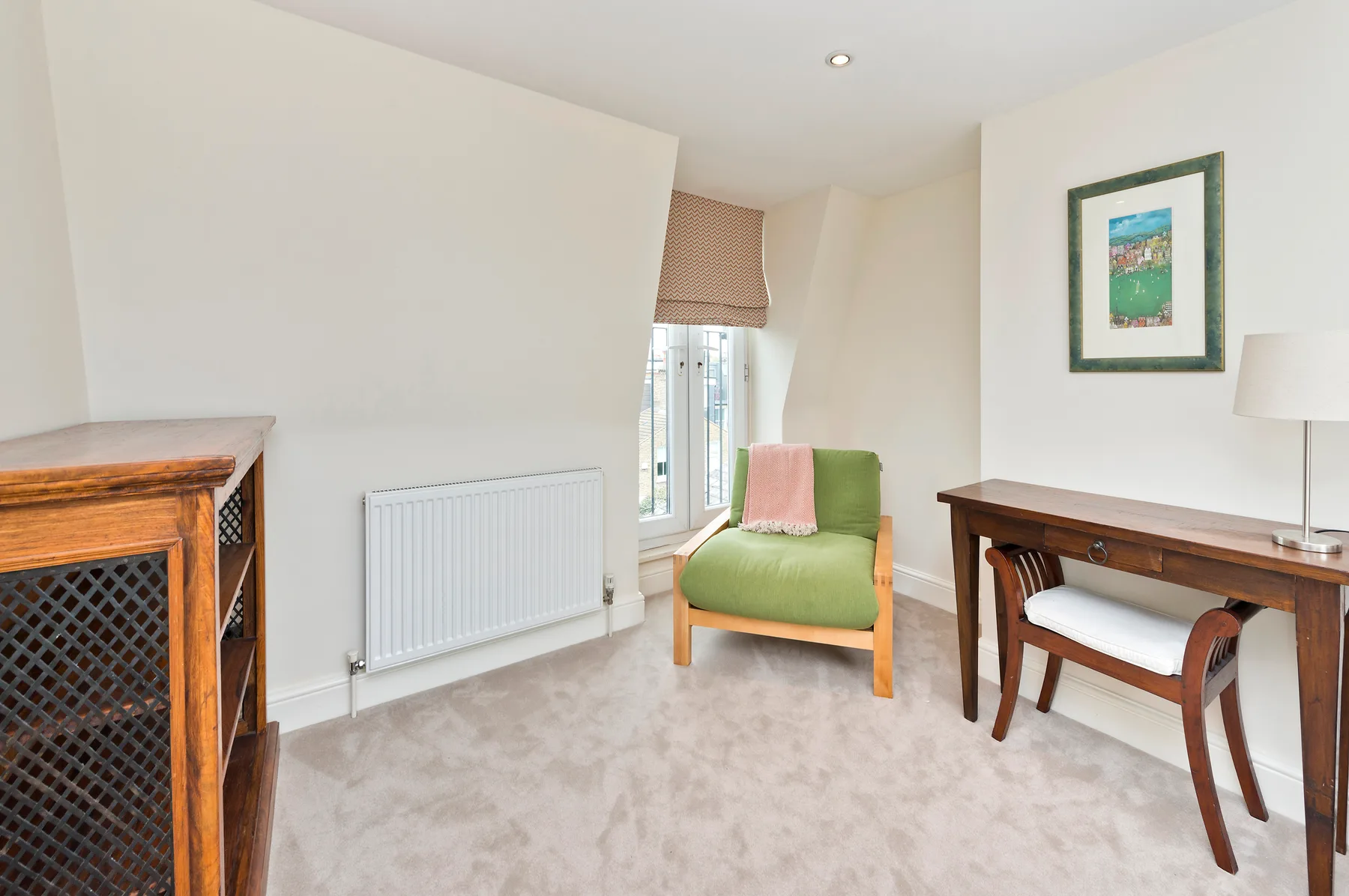 A bright sitting area with a green chair beside a window and writing desk.