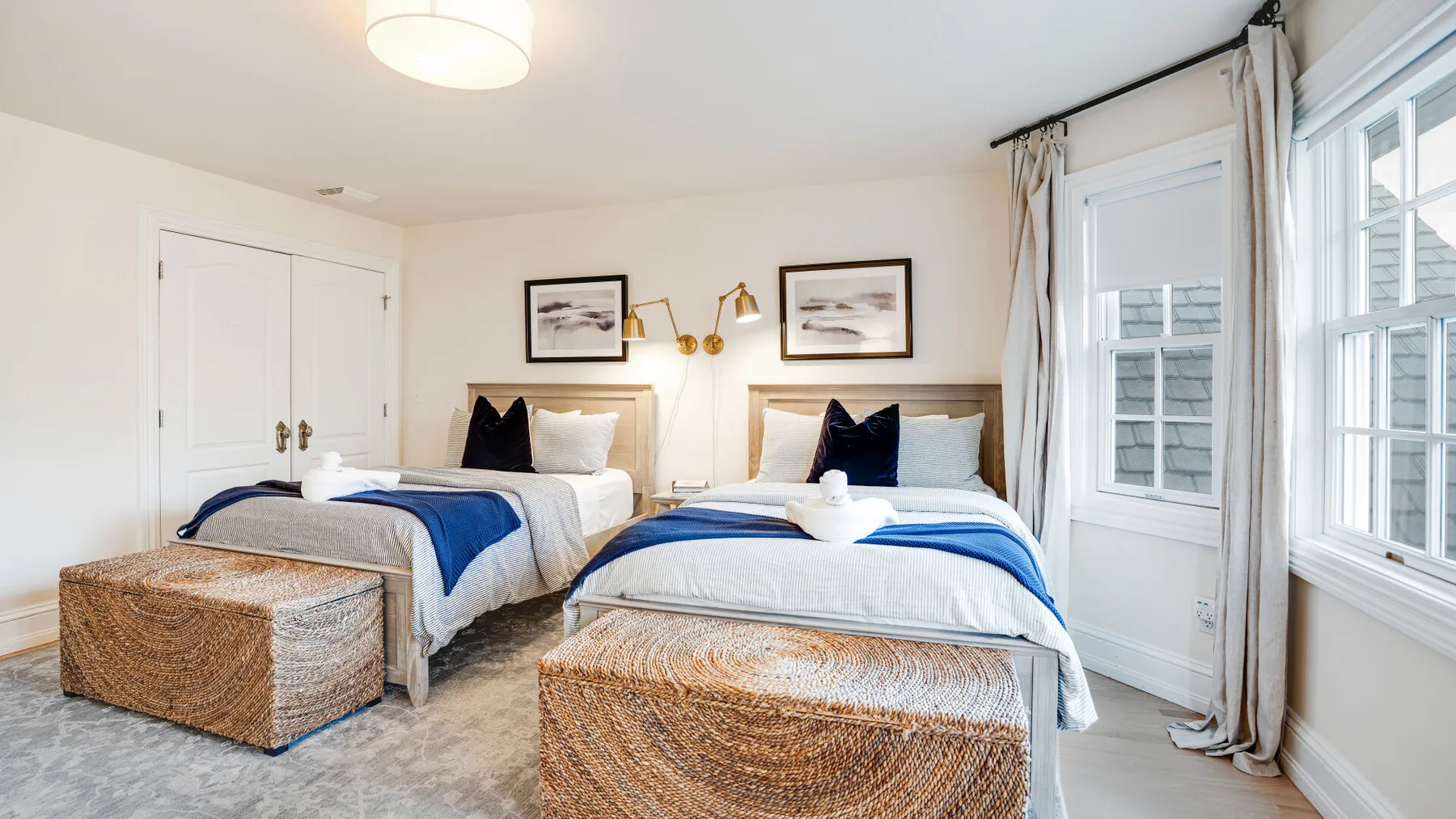 Un dormitorio luminoso con dos camas vestidas con ropa de cama blanca y azul.