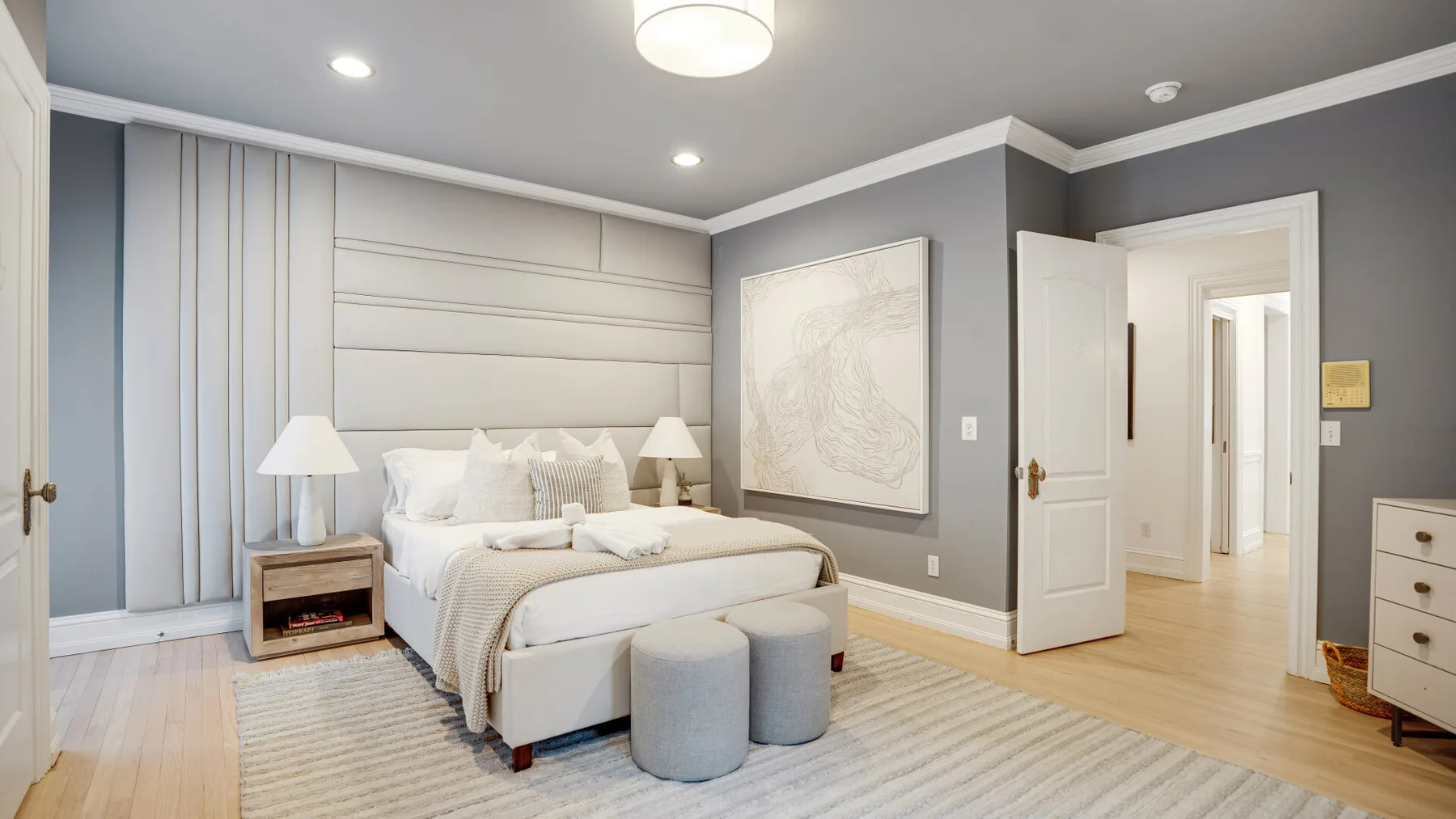 Un dormitorio con cama, mesitas de noche y una puerta abierta.