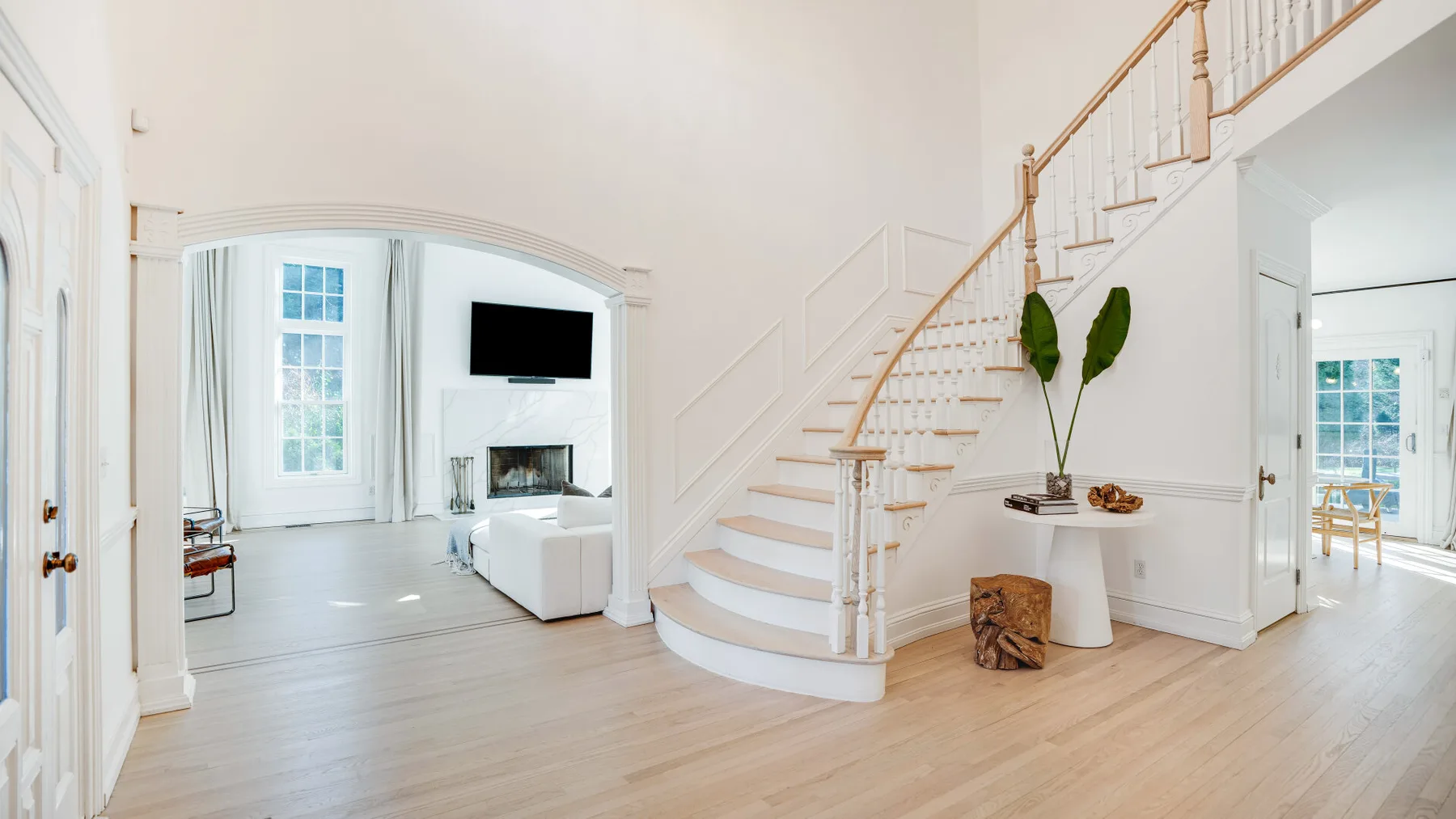 Una luminosa sala de estar se abre a una escalera curva y un comedor.