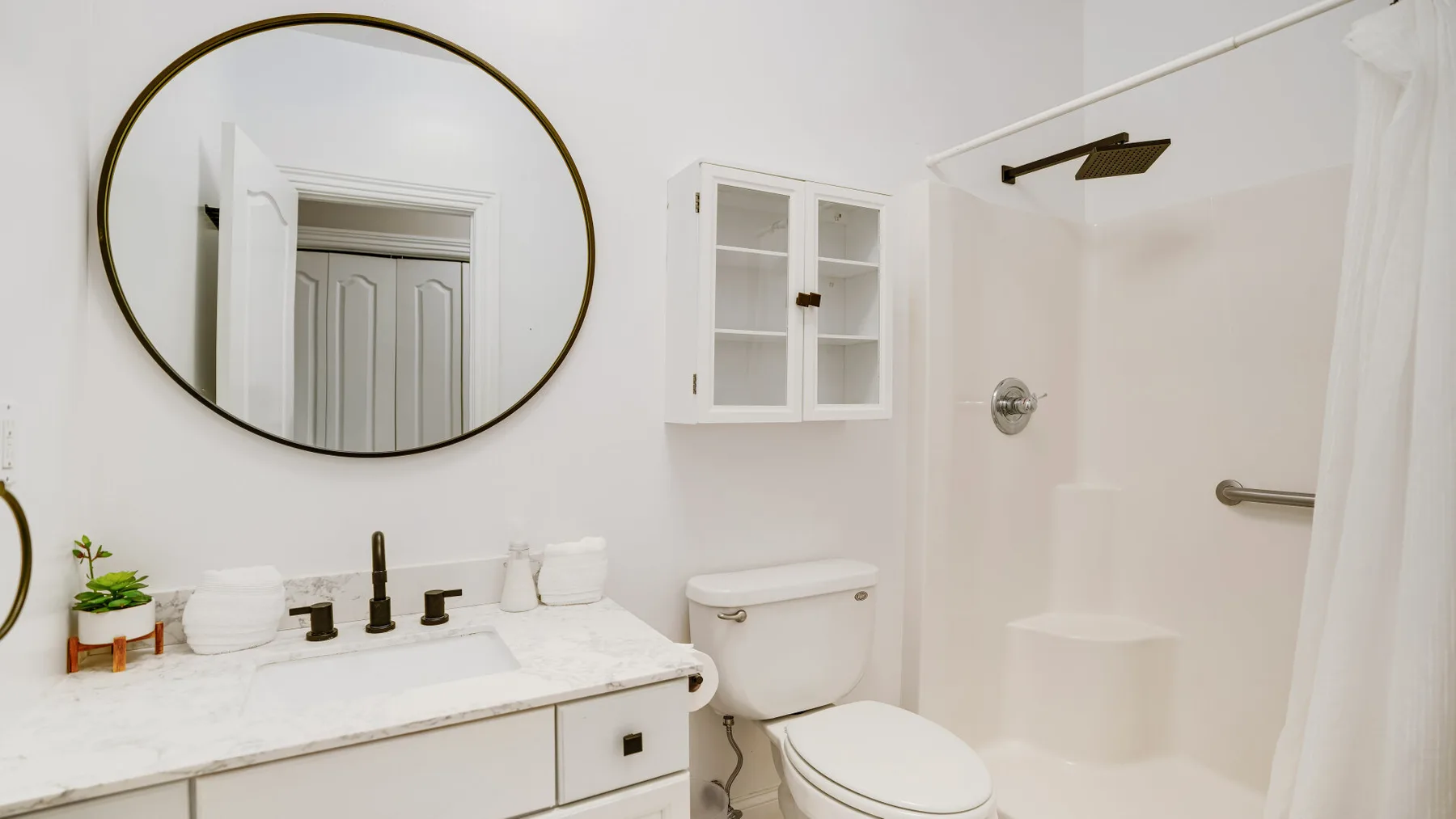 Un baño luminoso con lavabo, inodoro y ducha.