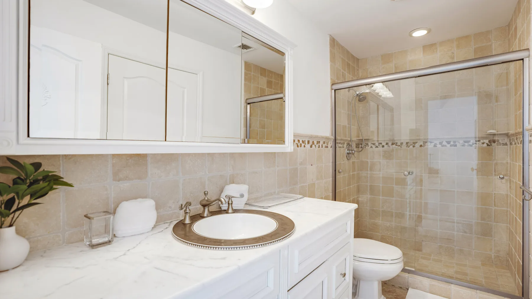 Un baño con lavabo, tocador y ducha con mampara de vidrio.