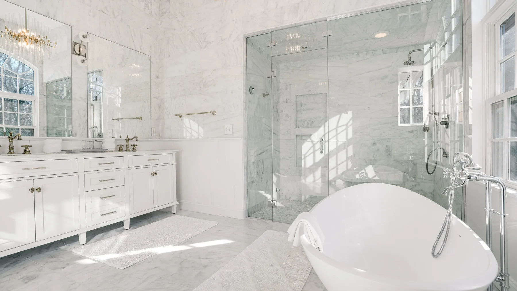 Un baño luminoso cuenta con una bañera exenta junto a una ducha de cristal.