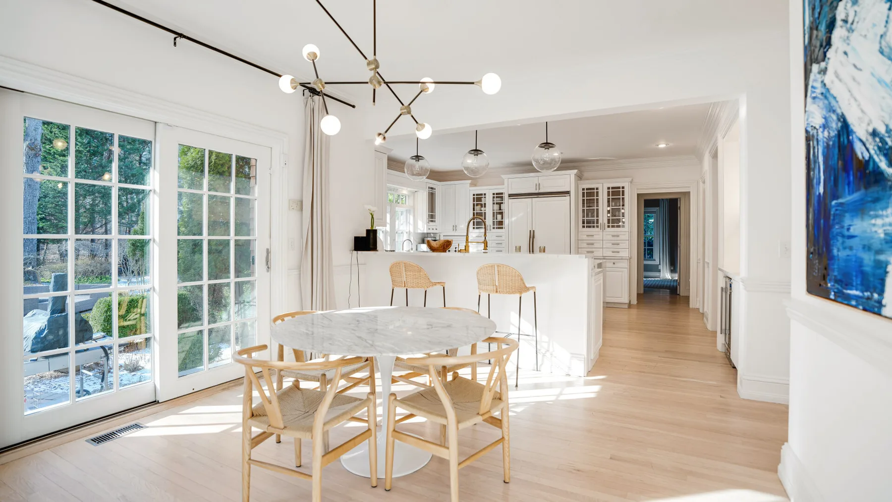 Un comedor luminoso se abre a una cocina, con una mesa redonda y sillas.