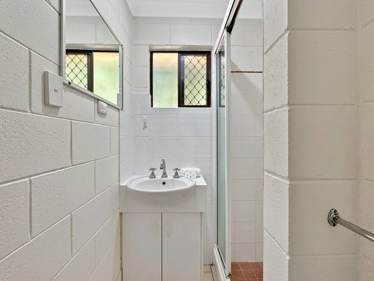 Un baño con lavabo, espejo y ventana.