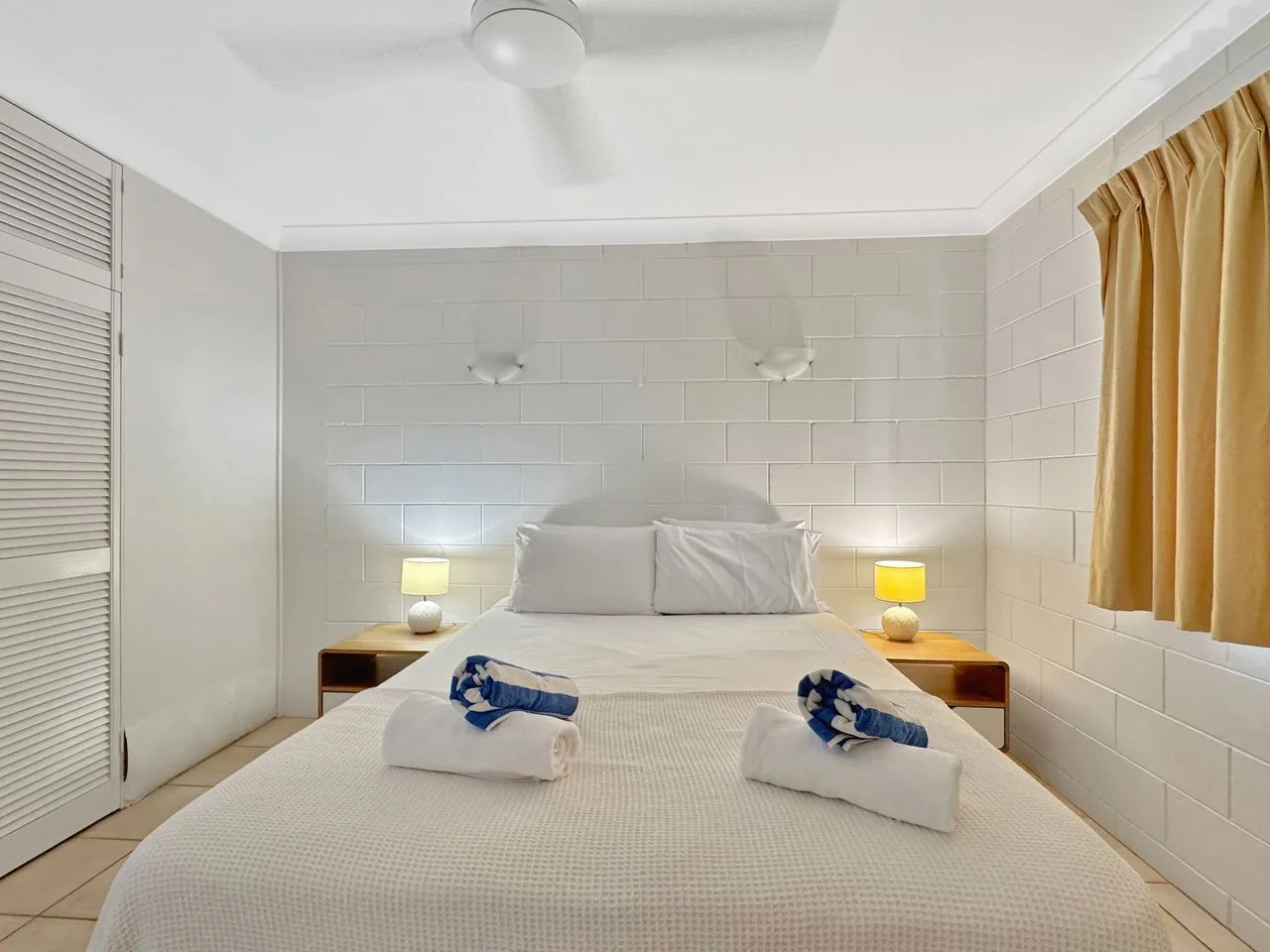 Un dormitorio con una cama bien tendida y cortinas junto a la ventana.