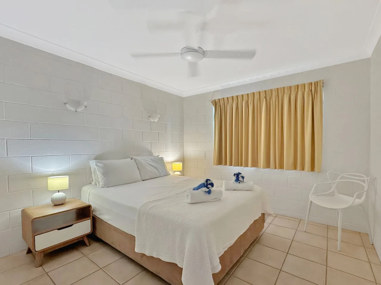 Un dormitorio con una cama doble, una mesita de noche y una ventana con cortinas.