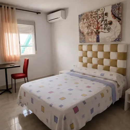 Habitación doble con una cama, escritorio y aire acondicionado.