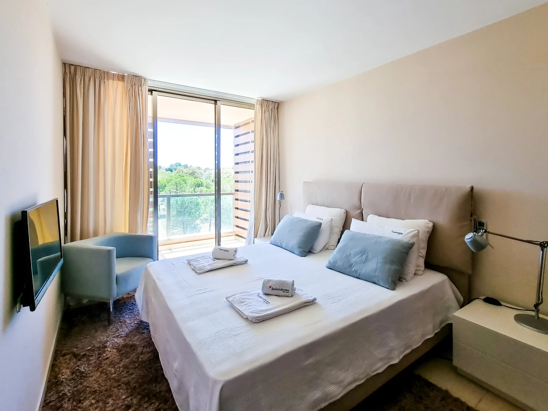 Un dormitorio con una cama bien hecha y puertas de vidrio que dan a un balcón.
