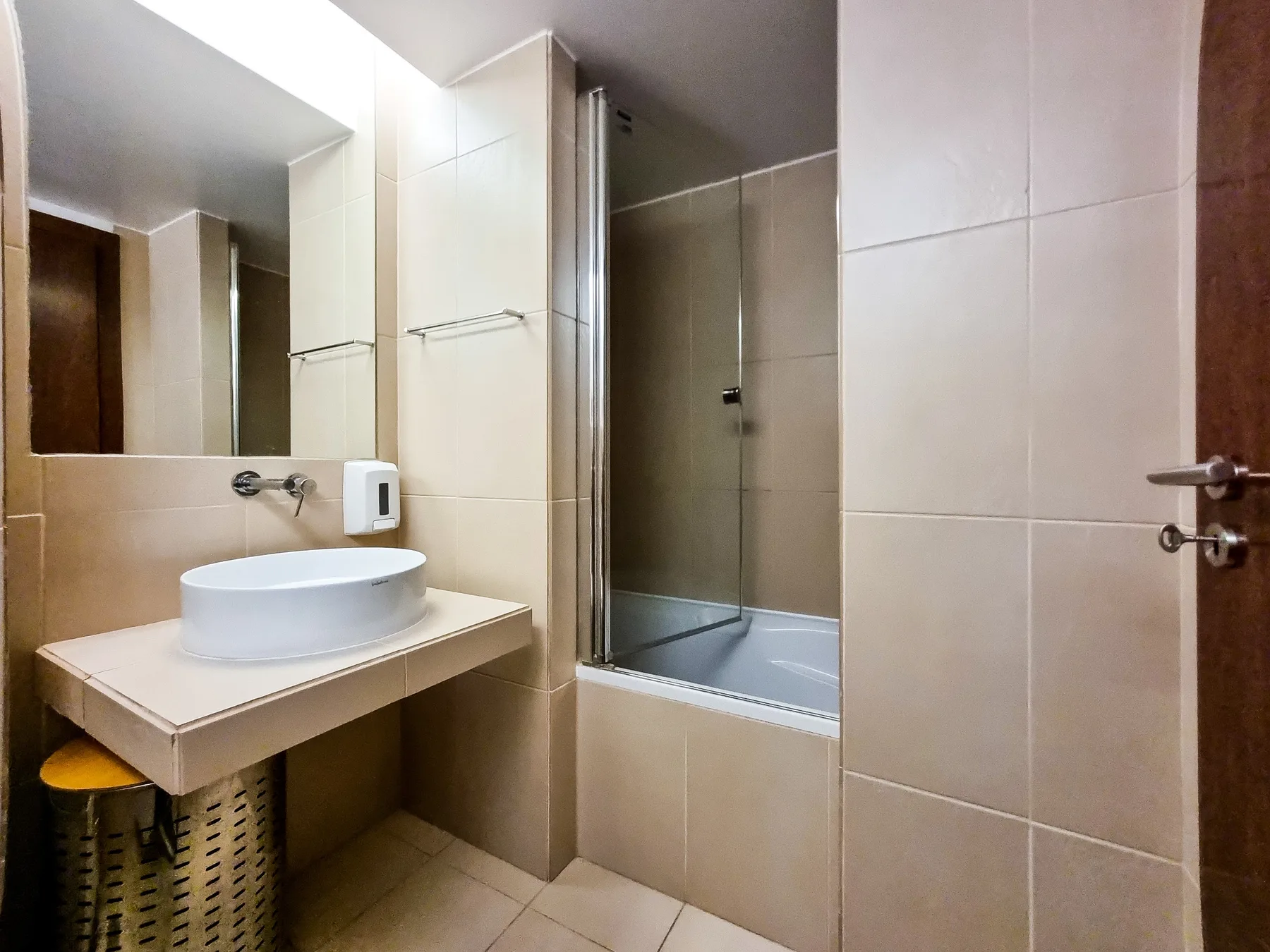 Un baño con azulejos, un lavabo suspendido y una ducha de vidrio.