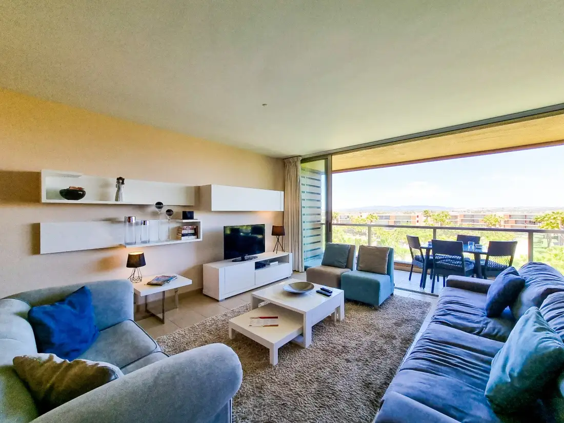 Living room with seating, a television, and sliding glass doors opening onto a balcony.