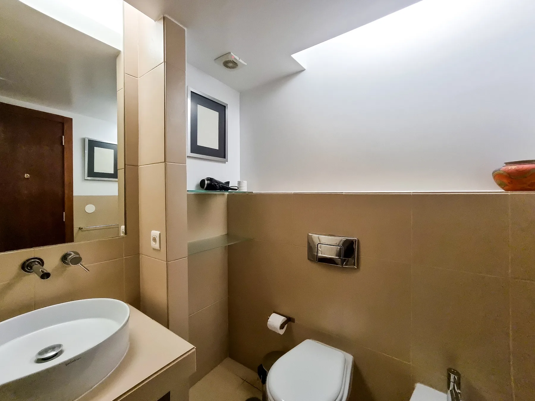 Un baño con lavabo, inodoro y paredes de azulejos.