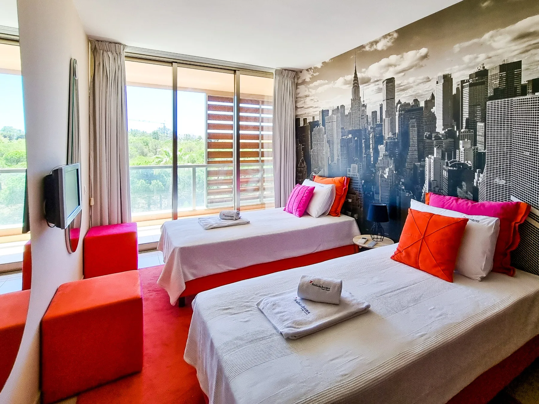 Un dormitorio con dos camas, almohadas coloridas y un gran mural urbano.