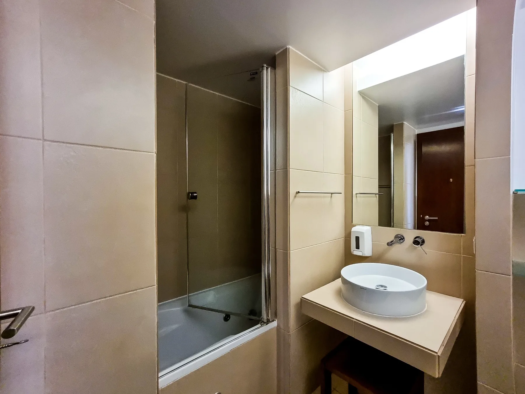 Un baño con ducha de vidrio y lavabo sobre una encimera.