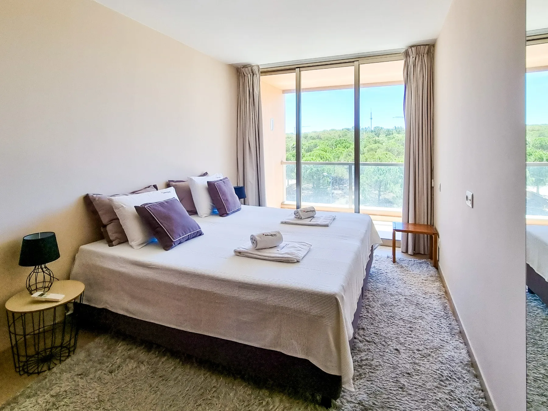 Un dormitorio luminoso con una cama grande y puertas correderas de cristal que dan a un balcón.