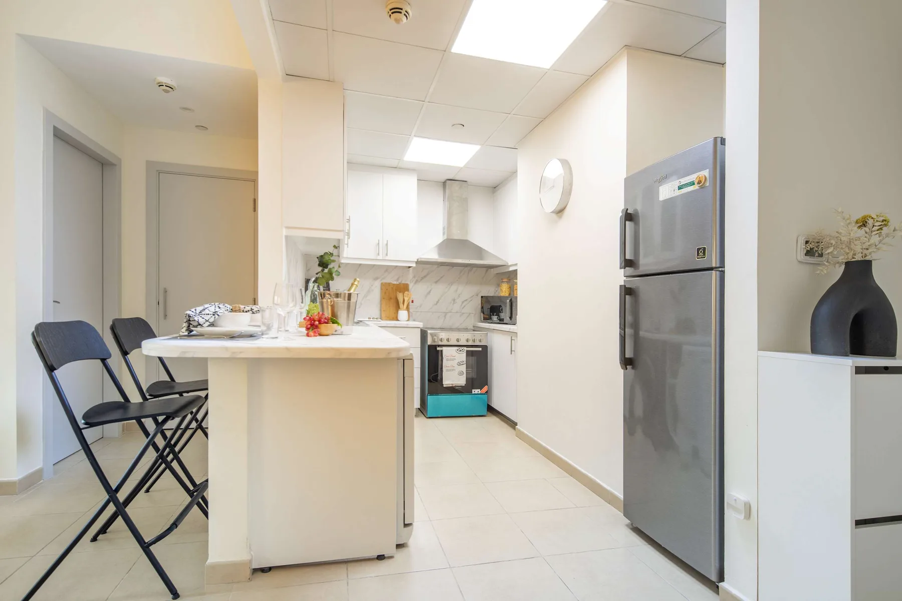 Una cocina luminosa con barra, zona de cocción y refrigerador.