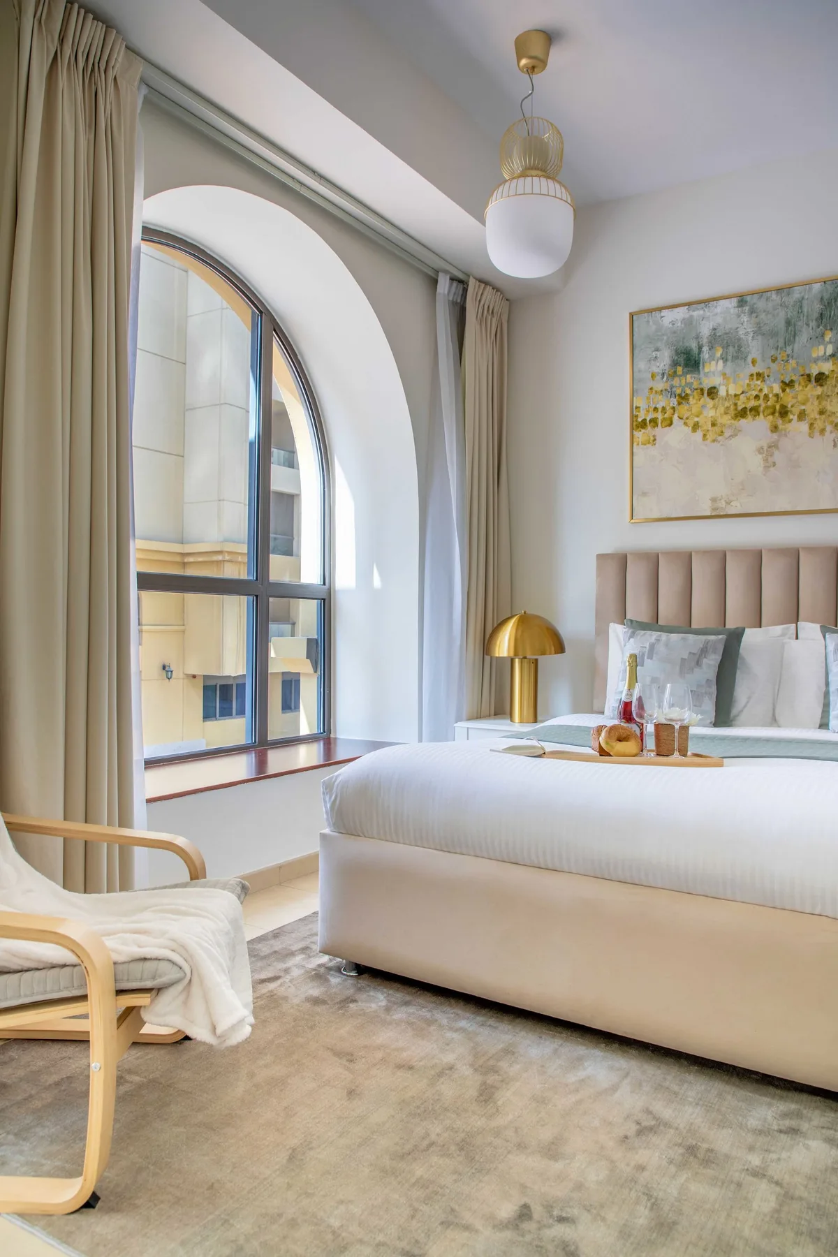 Un dormitorio luminoso con una gran ventana arqueada junto a la cama.