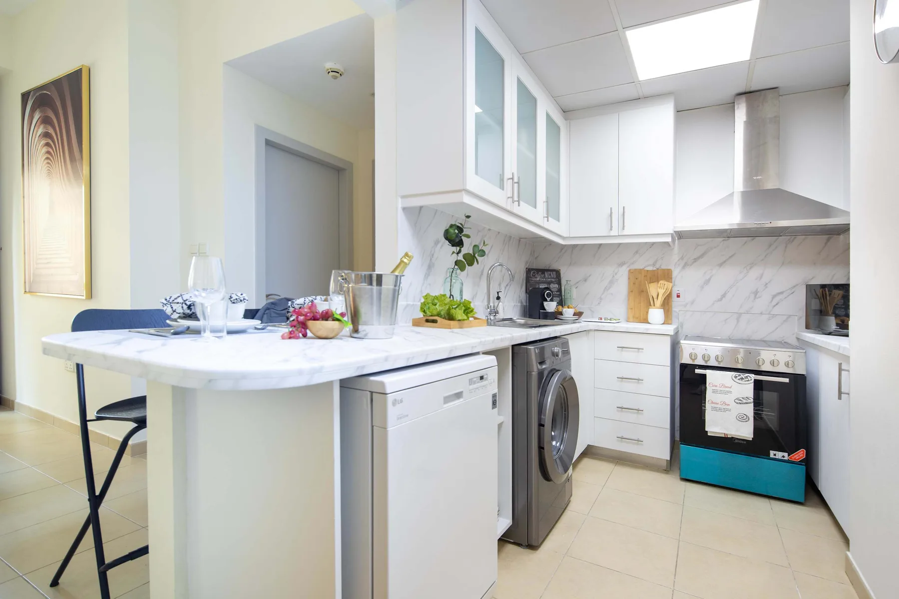 Una cocina luminosa con una isla central, gabinetes blancos y electrodomésticos integrados.