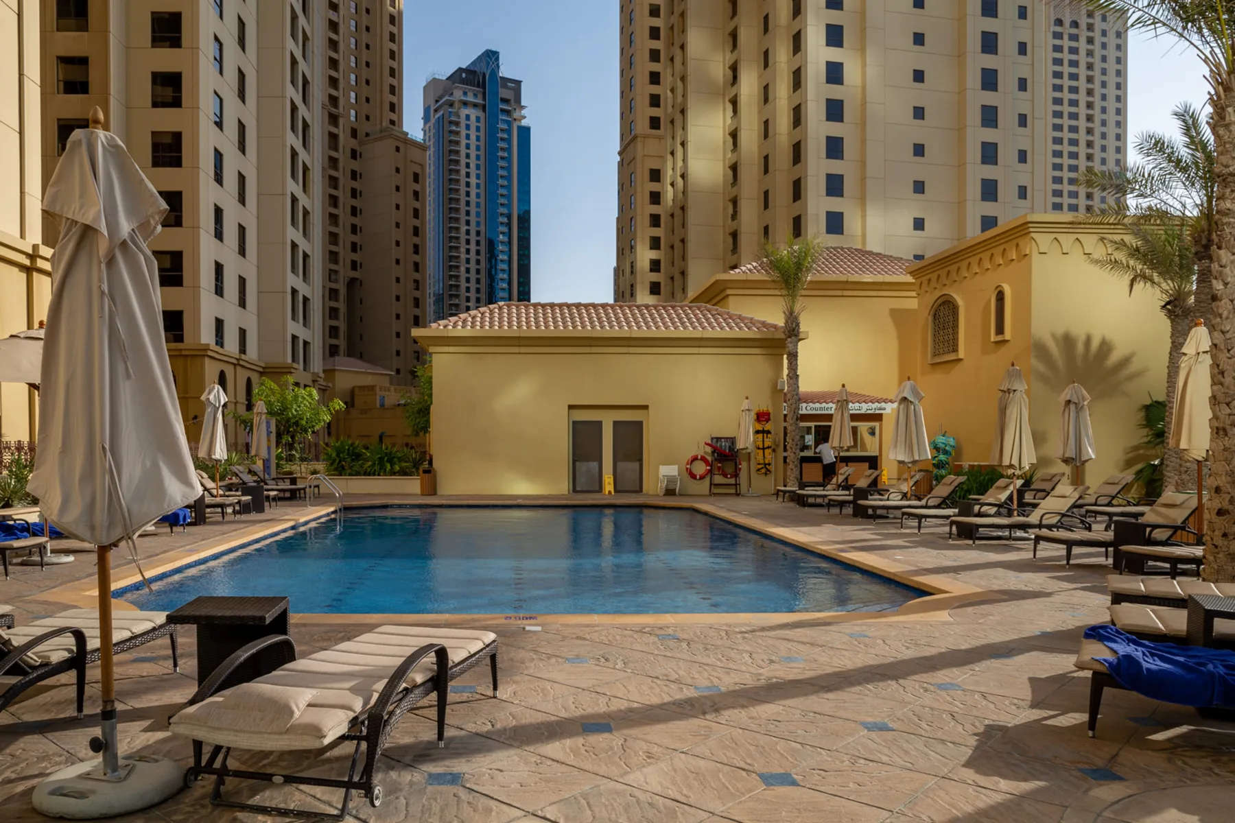 Una piscina al aire libre y asientos de descanso están rodeados de edificios residenciales altos.