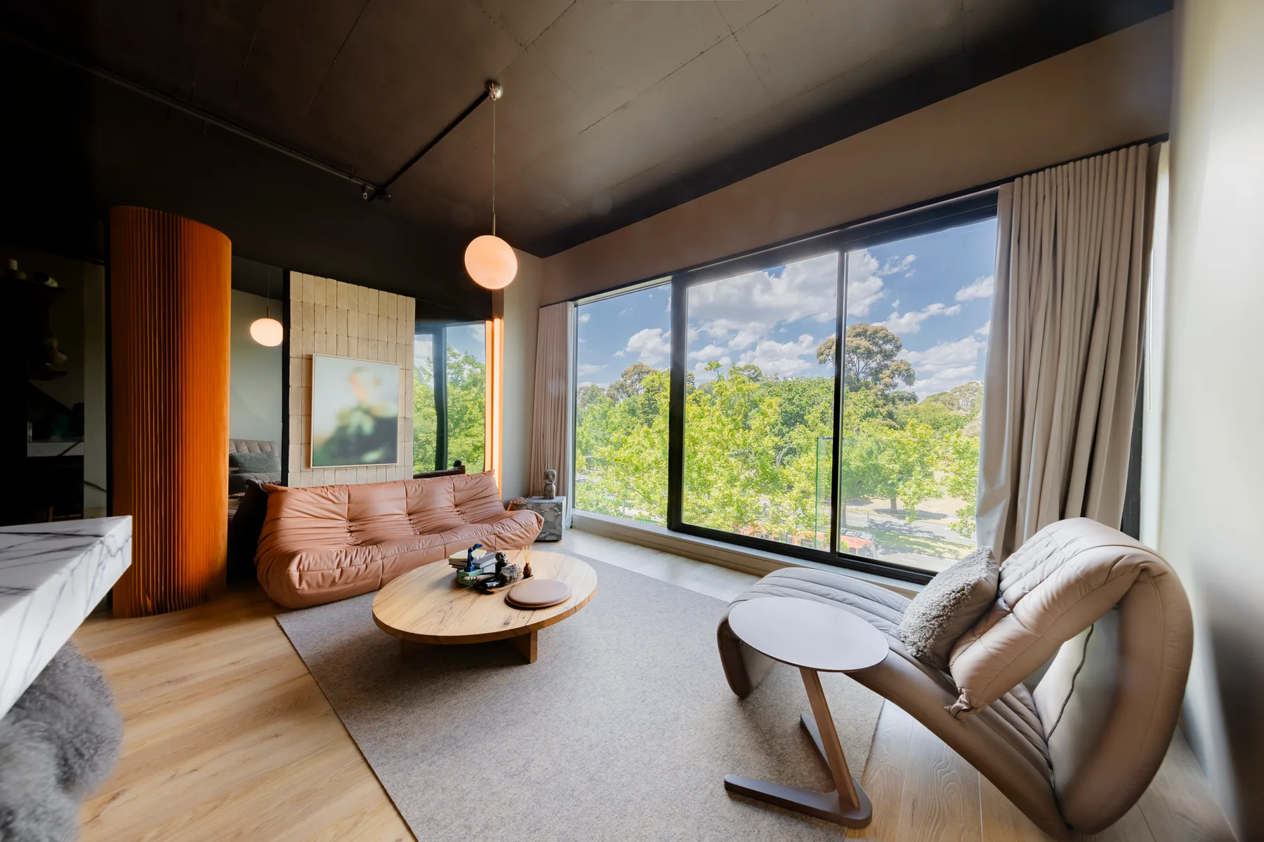 Una sala de estar con asientos junto a grandes ventanales con vistas a zonas verdes.