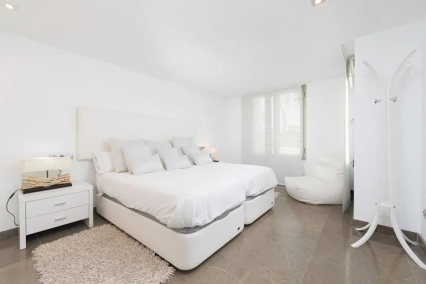 Un dormitorio luminoso con una cama grande, una mesita de noche y una alfombra suave.