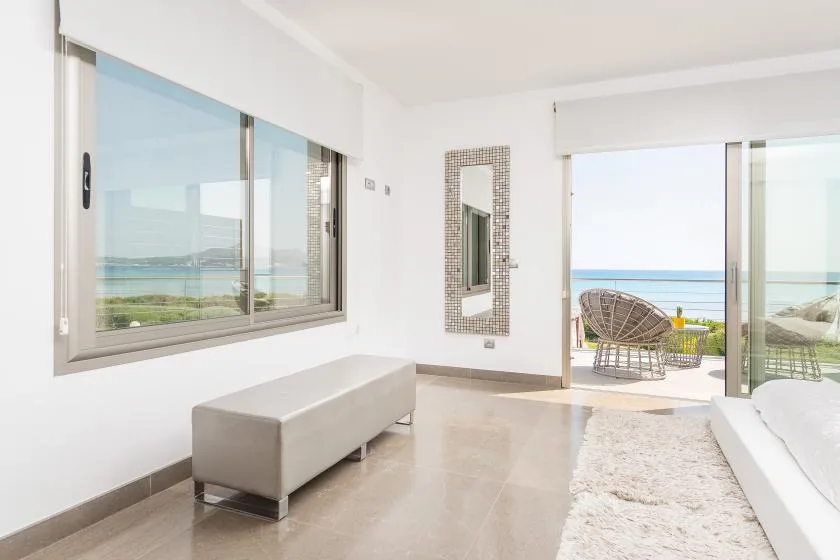 Un dormitorio luminoso se abre a un balcón con asientos y vistas al mar.