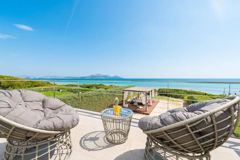 A sunny outdoor patio with cushioned seating overlooking the sea.
