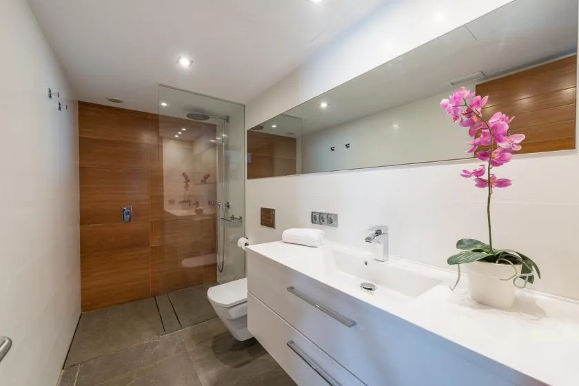 Un baño moderno con una encimera larga de lavabo y una ducha de vidrio.