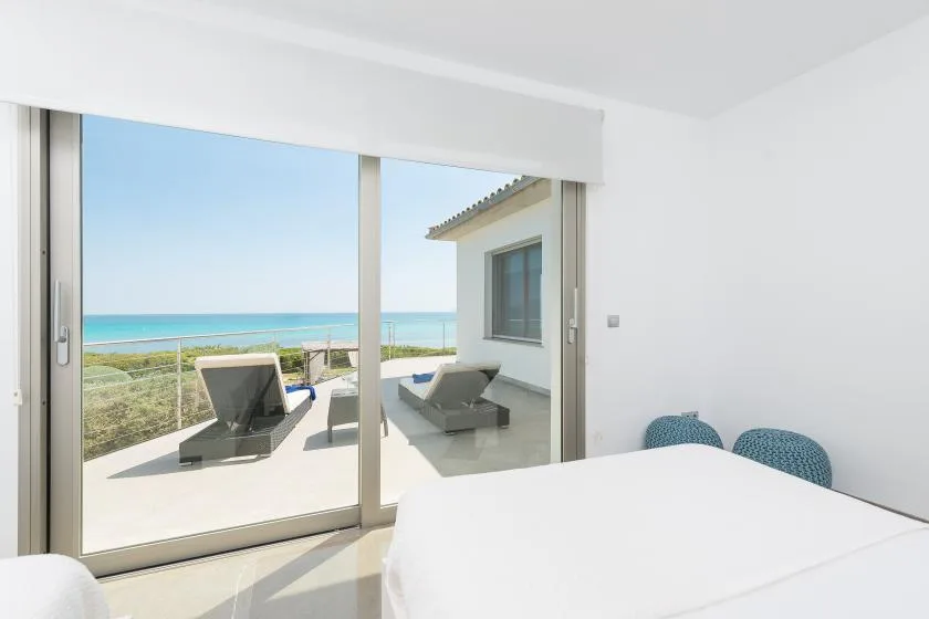 Un dormitorio luminoso da a una terraza con asientos y vistas al mar.