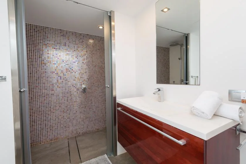 Un lavabo de baño con un espejo amplio y una ducha con azulejos.