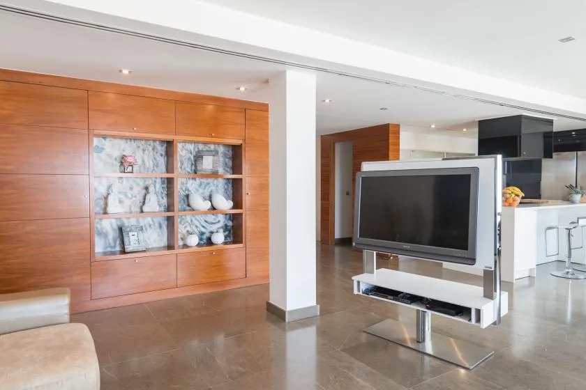 Una sala de estar de concepto abierto con un televisor junto a una pared de madera con estantes.