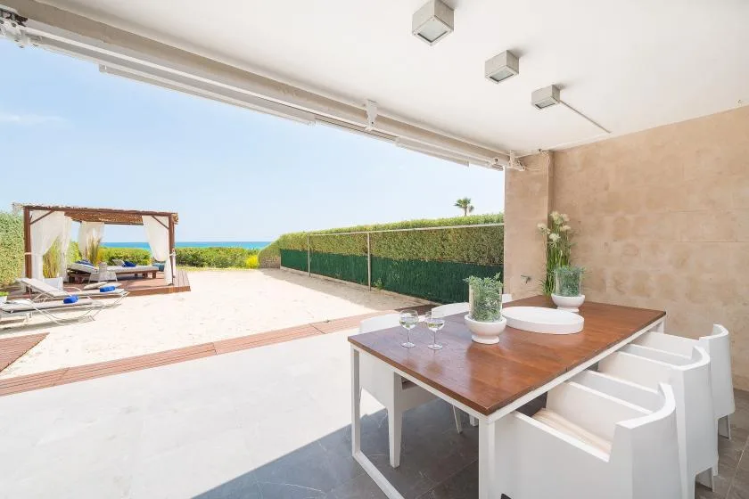 Una zona de comedor al aire libre da a un patio soleado con vistas al mar.