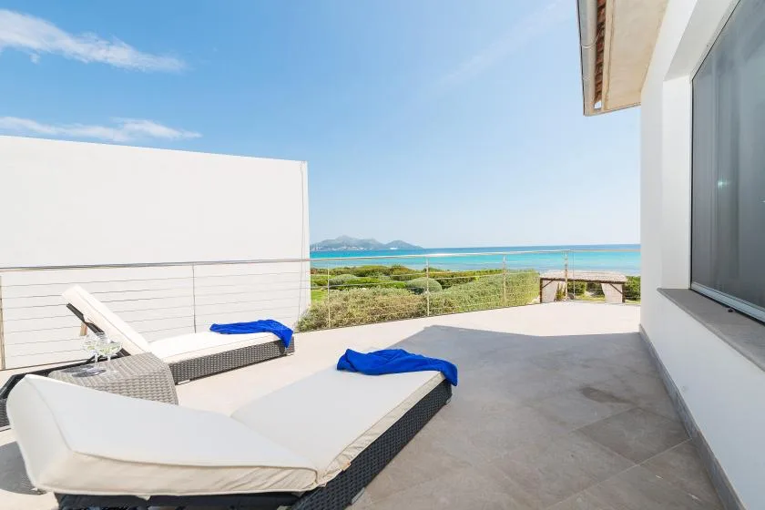 Una terraza soleada con asientos reclinables ofrece vistas al mar.