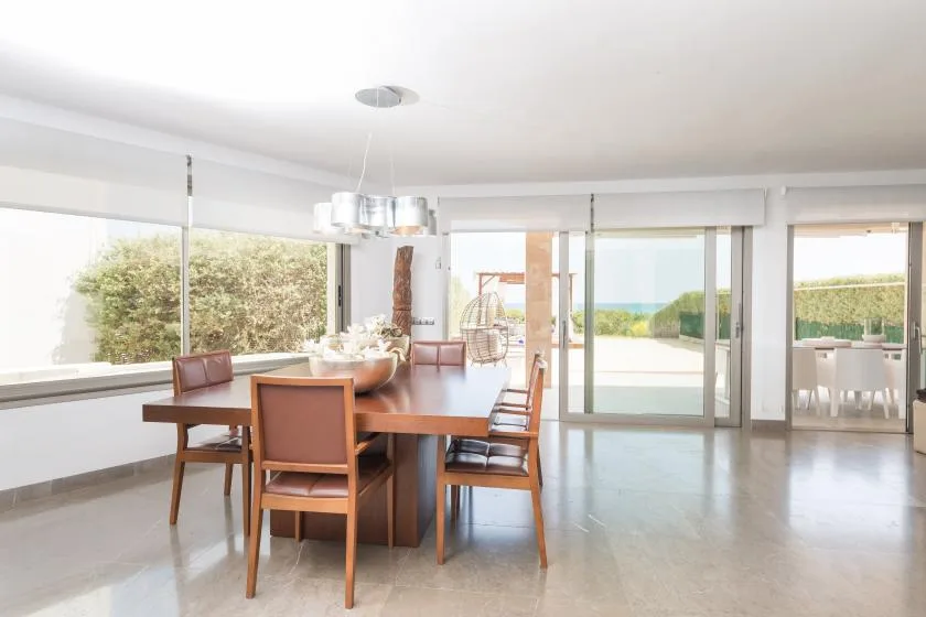 Una luminosa zona de comedor da a un patio a través de amplias puertas de vidrio.