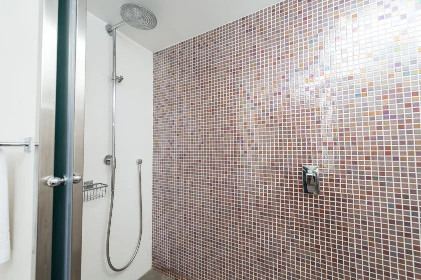 Una zona de ducha con azulejos, cabezal de ducha y ducha de mano.