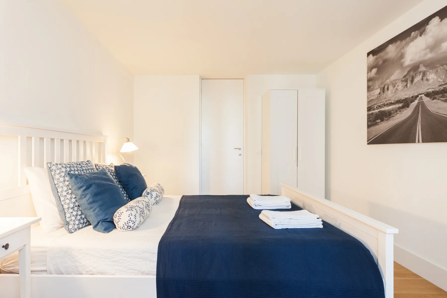 A bright bedroom with a neatly made bed and folded towels.
