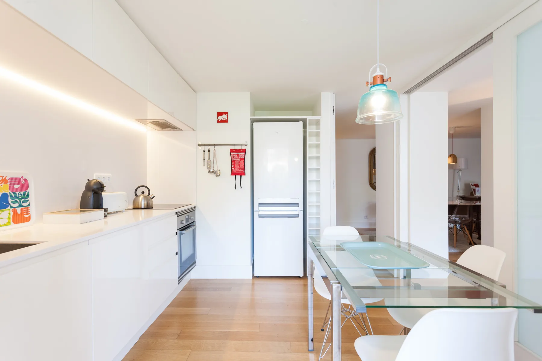 A bright kitchen and dining area with white cabinetry and a glass table.