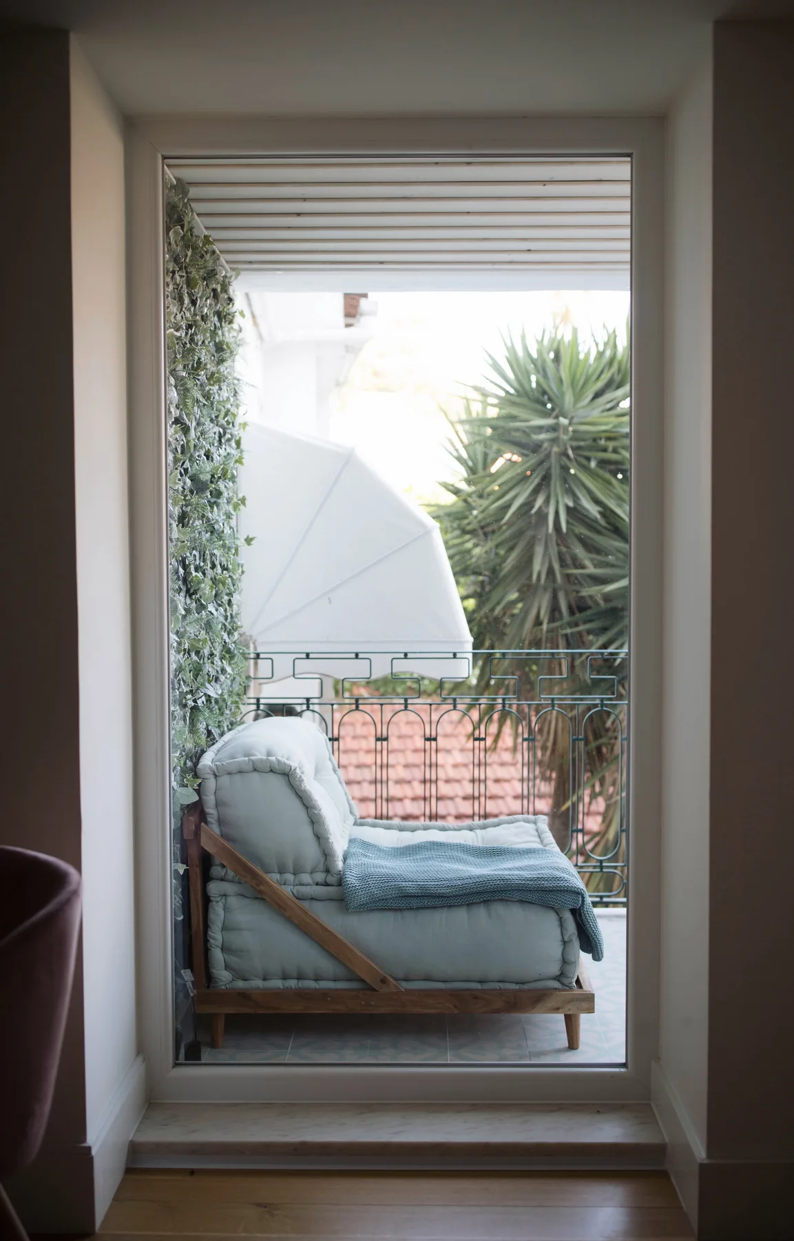 A view through a doorway shows an outdoor seating area with leafy plants.