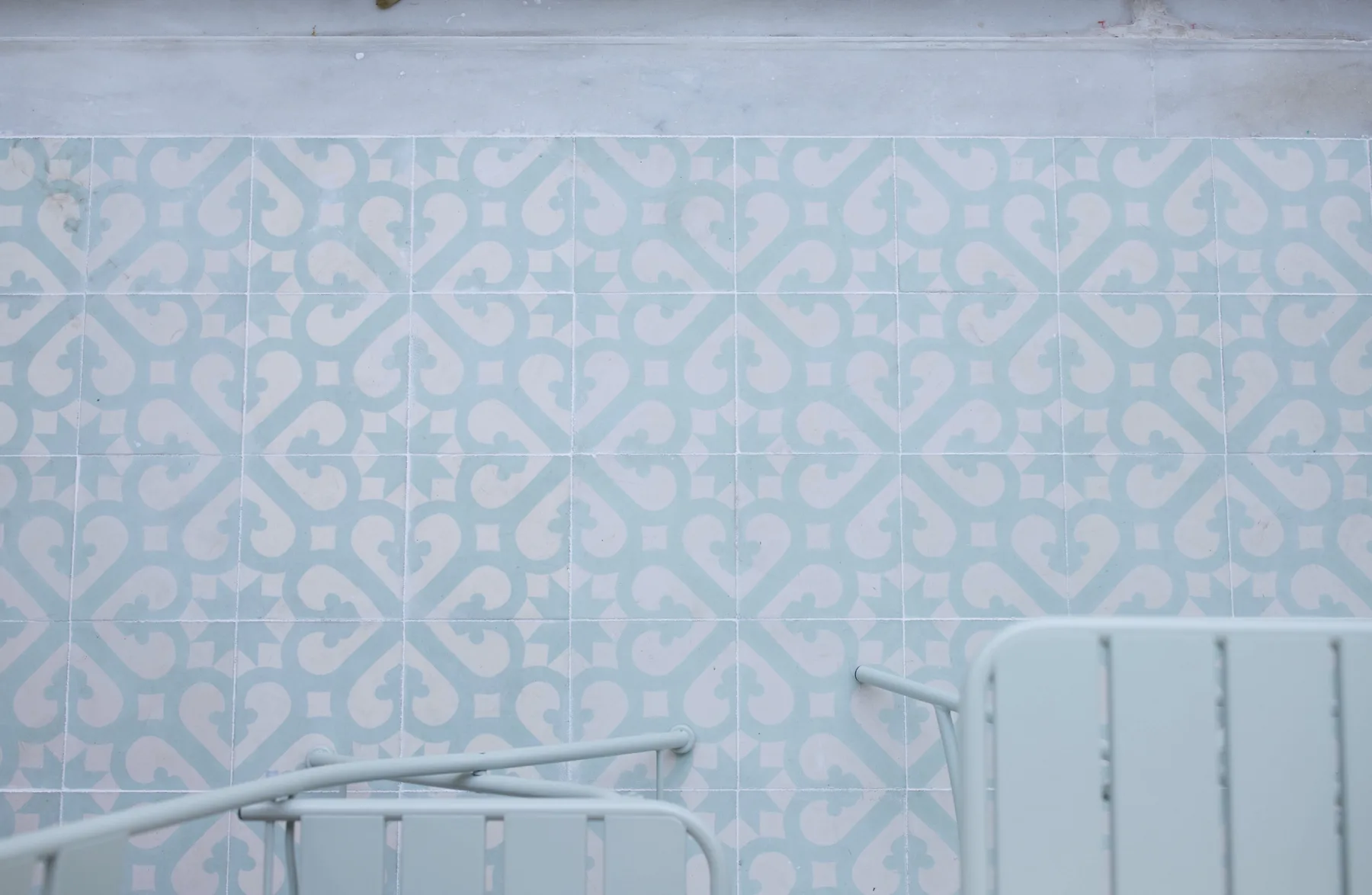 A tiled balcony with pale blue patterned walls and metal railings.