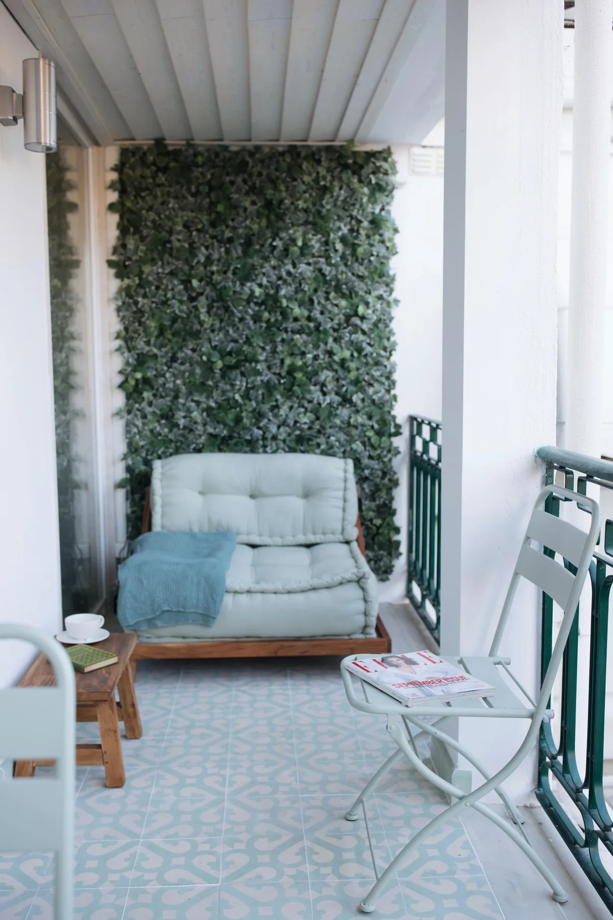 A covered terrace with seating and a leafy wall.