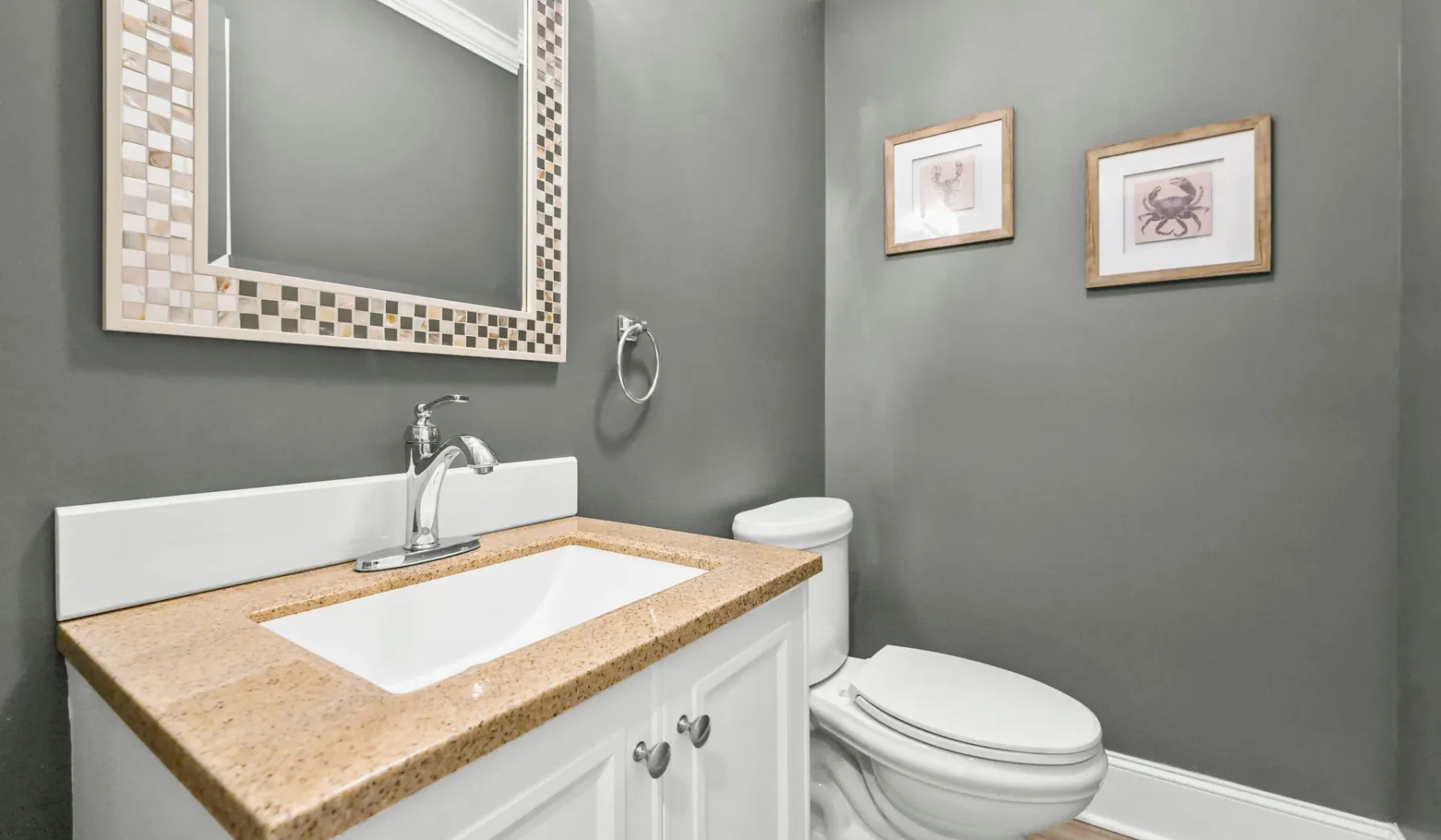 Un baño con lavabo, inodoro y cuadros en la pared.
