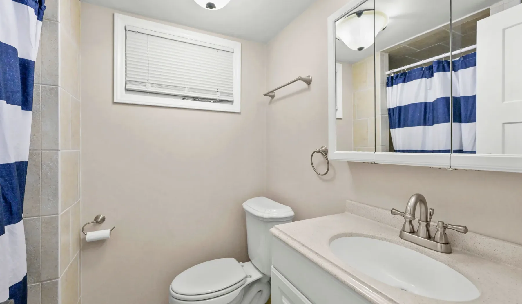 Un baño con lavabo, inodoro y cortina de ducha a rayas azules y blancas.