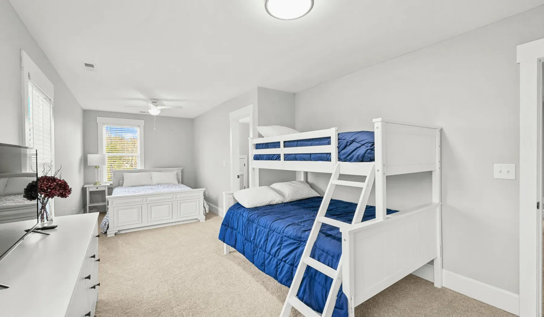 Un dormitorio con literas blancas y ropa de cama azul.