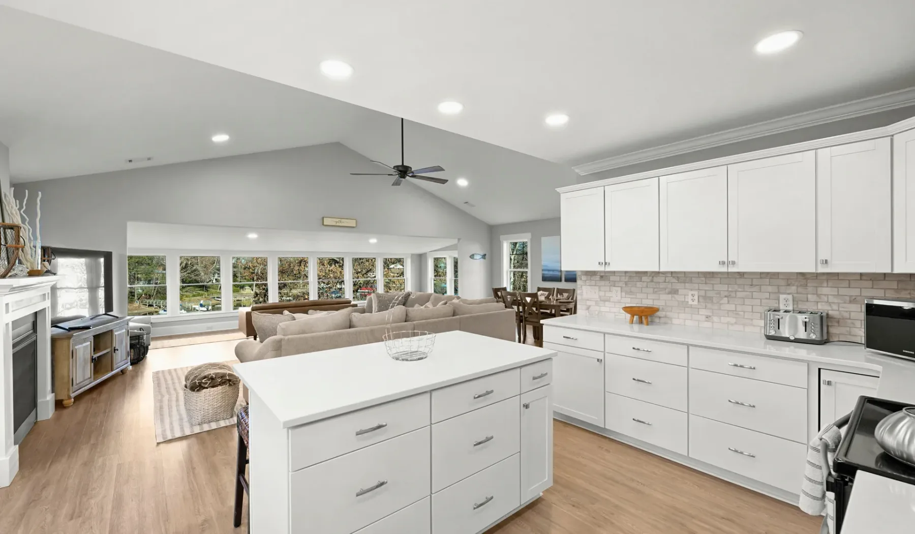 Cocina y sala de estar de planta abierta, con gabinetes blancos y una isla central.