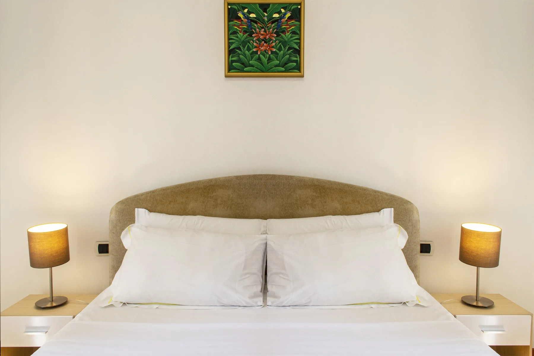 Un dormitorio con una cama tendida y lámparas de noche a juego.
