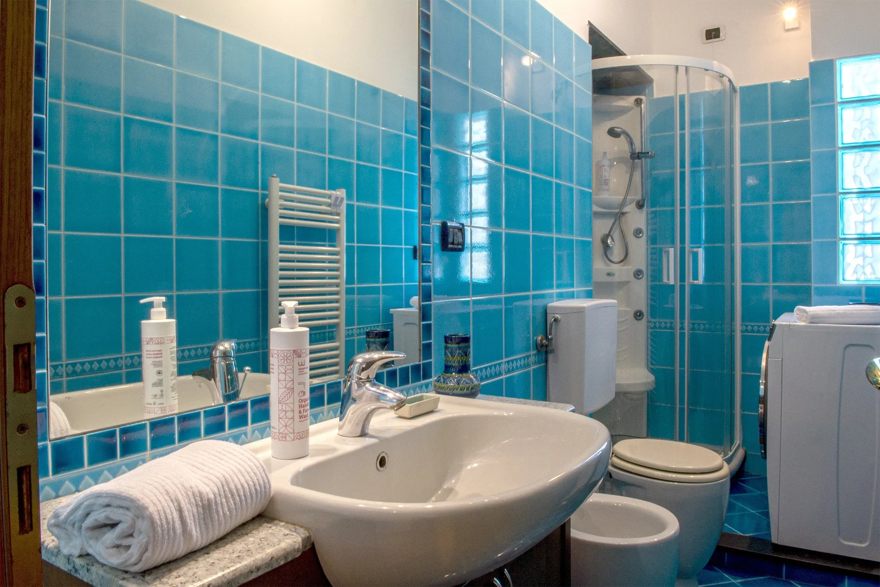 Un baño con lavabo, inodoro y paredes de azulejos azules.