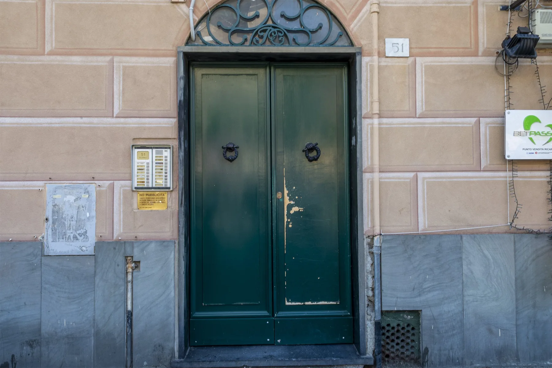 Una puerta doble verde oscura está empotrada en la fachada clara de un edificio.