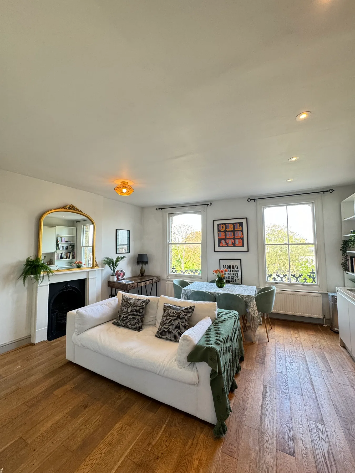 A bright living room with white seating and a dining table by the windows.